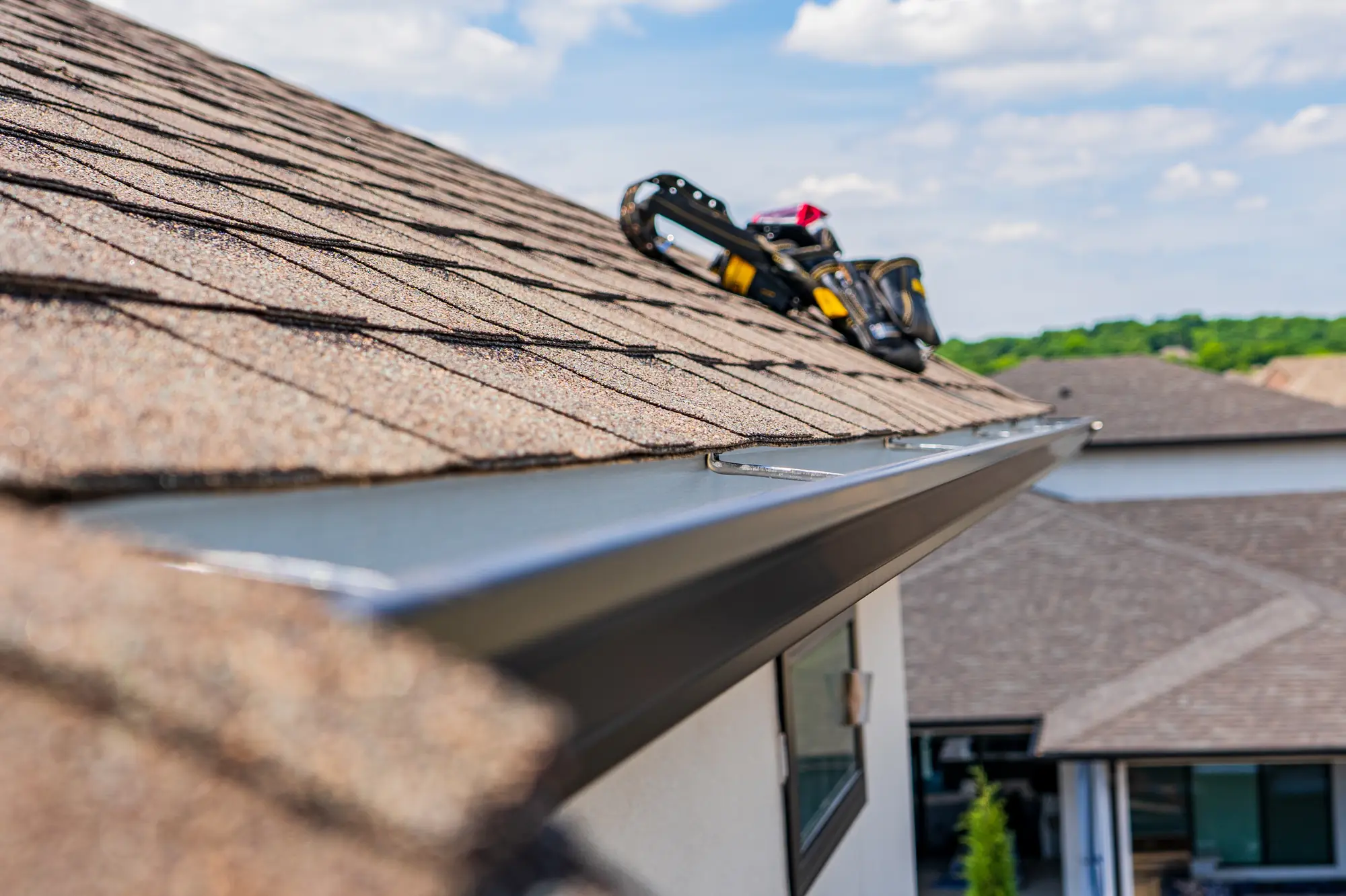Seamless gutter running along the eave of a shingled roof