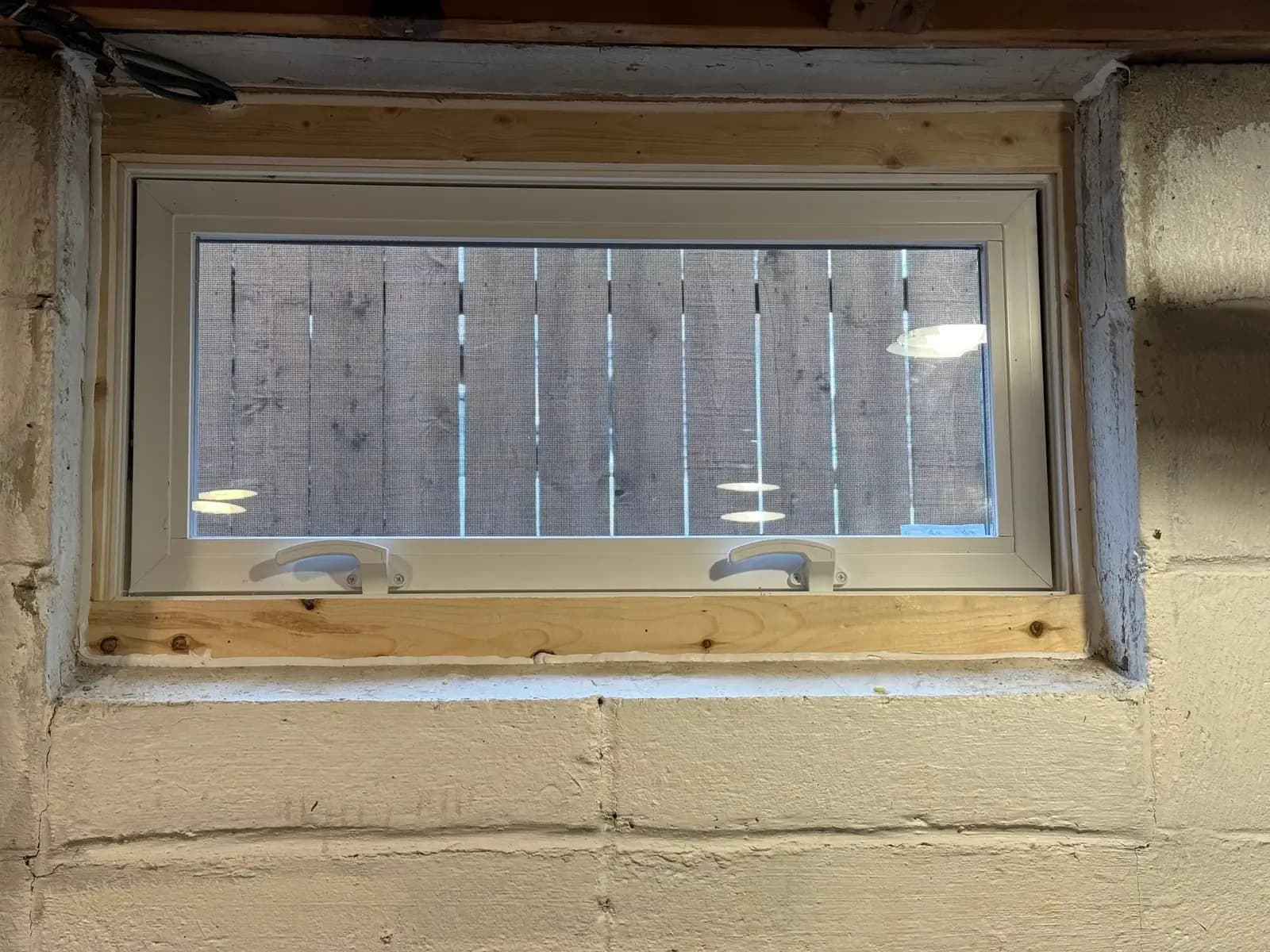 New hopper window set into a block foundation wall