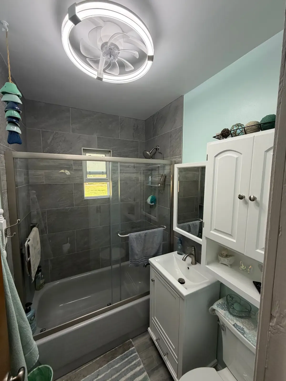 Finished bathroom with a tiled tub surround, glass doors and a new vanity