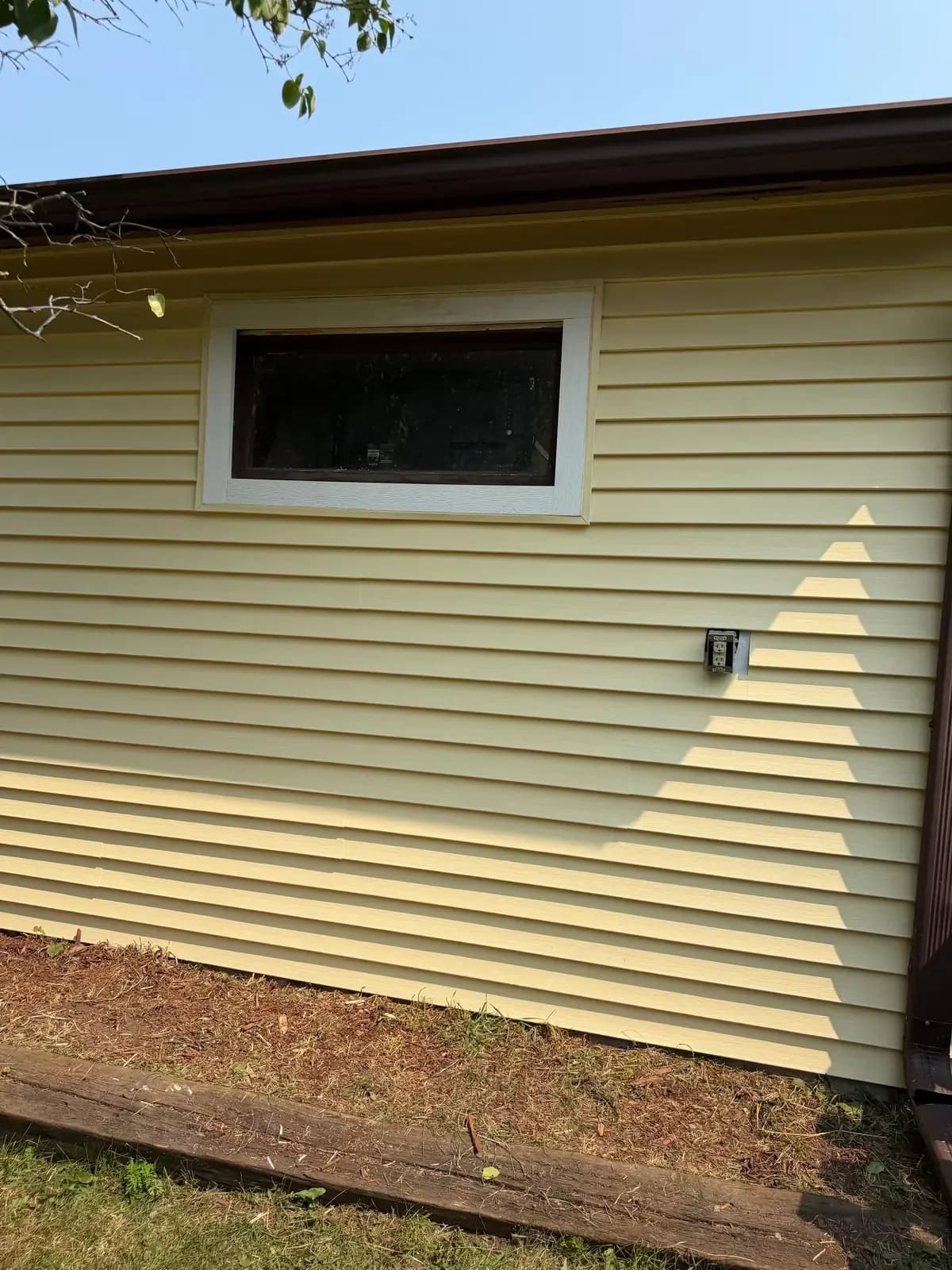 New lap siding running under a soffit and gutter, with a trimmed window opening