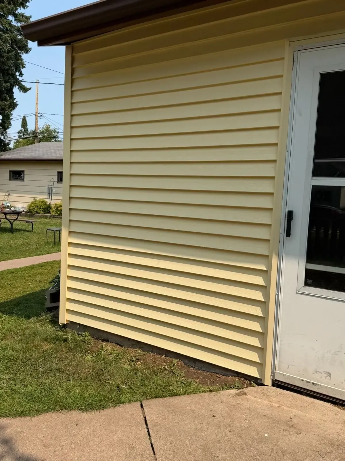 Outside corner of a home in new lap siding, meeting a door surround and the soffit above